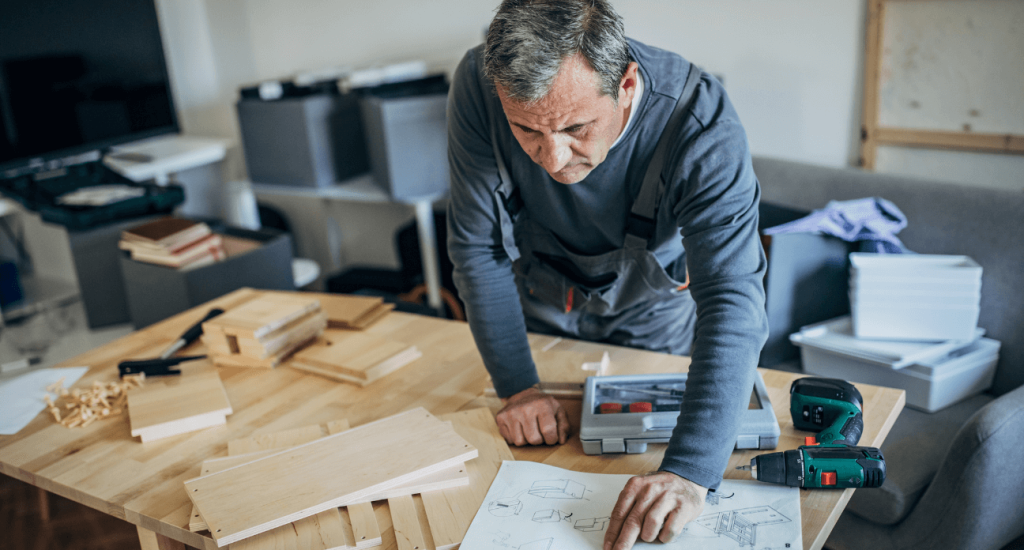 man referring to instruction manual while putting together wooden pieces